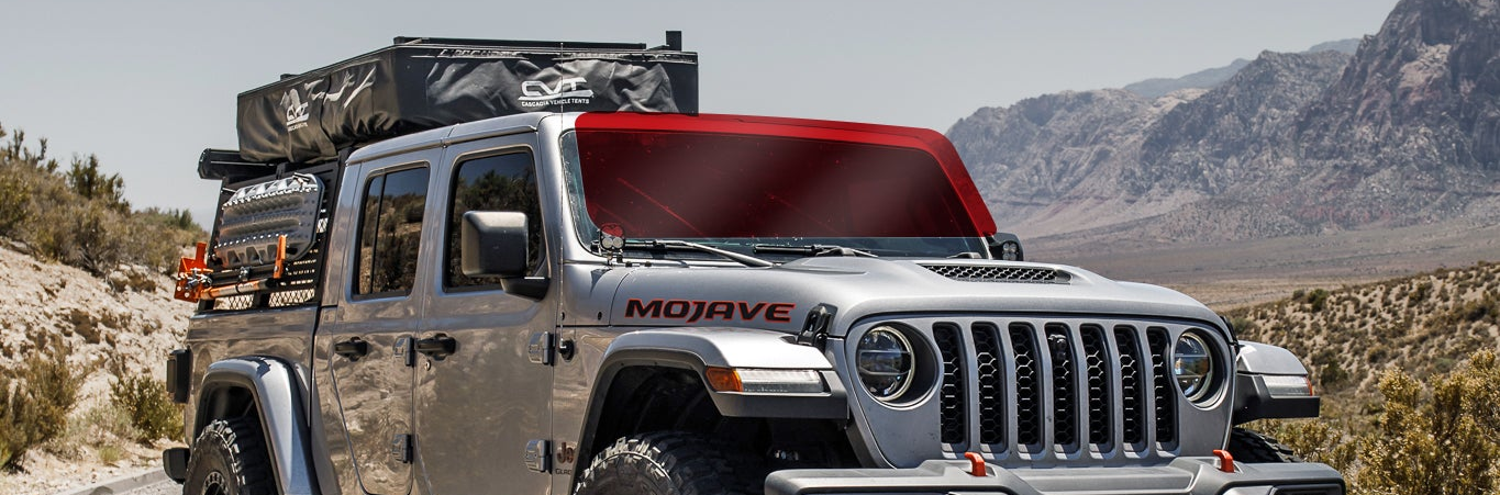 Silver Jeep Wrangler with roof rack in desert landscape